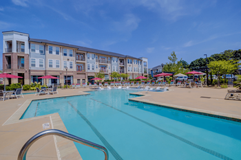 A large swimming pool in front of a multi-story apartment building.